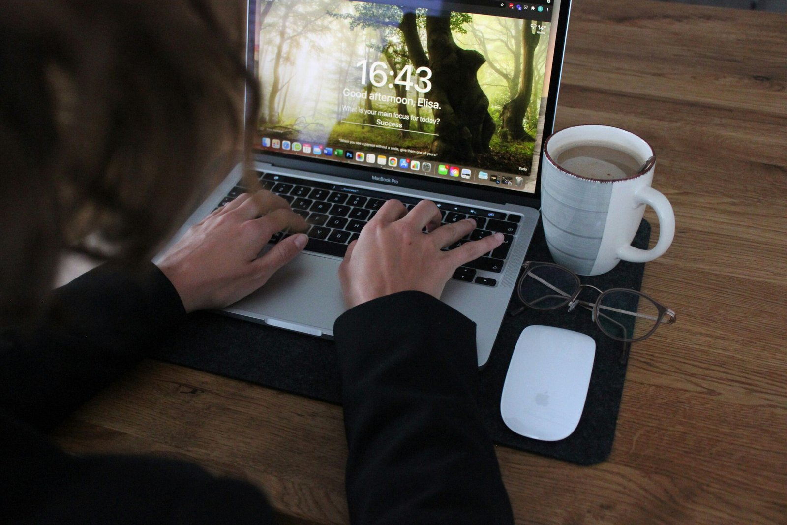 person using macbook pro on brown wooden table