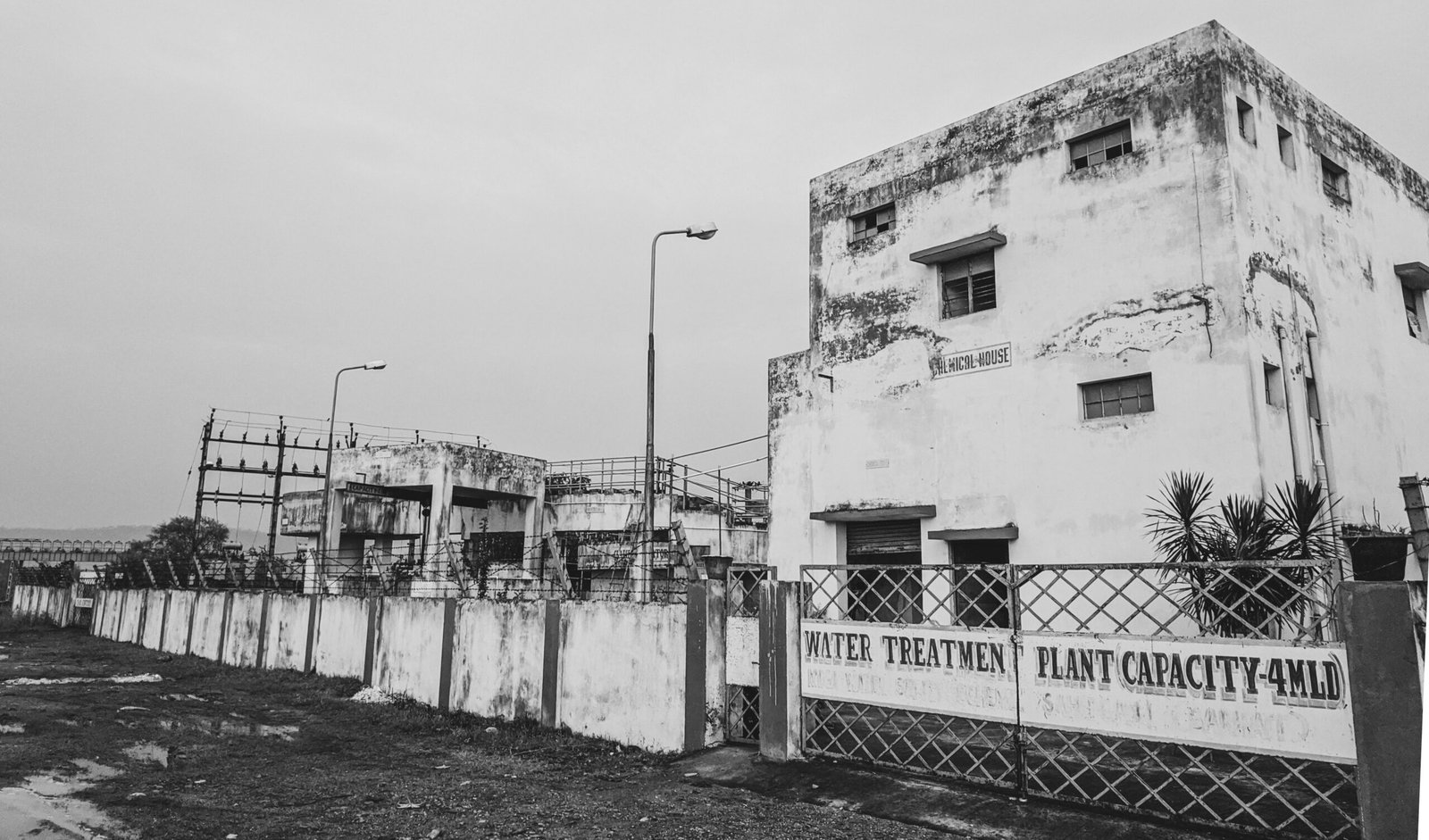 grayscale photo of metal fence near concrete building