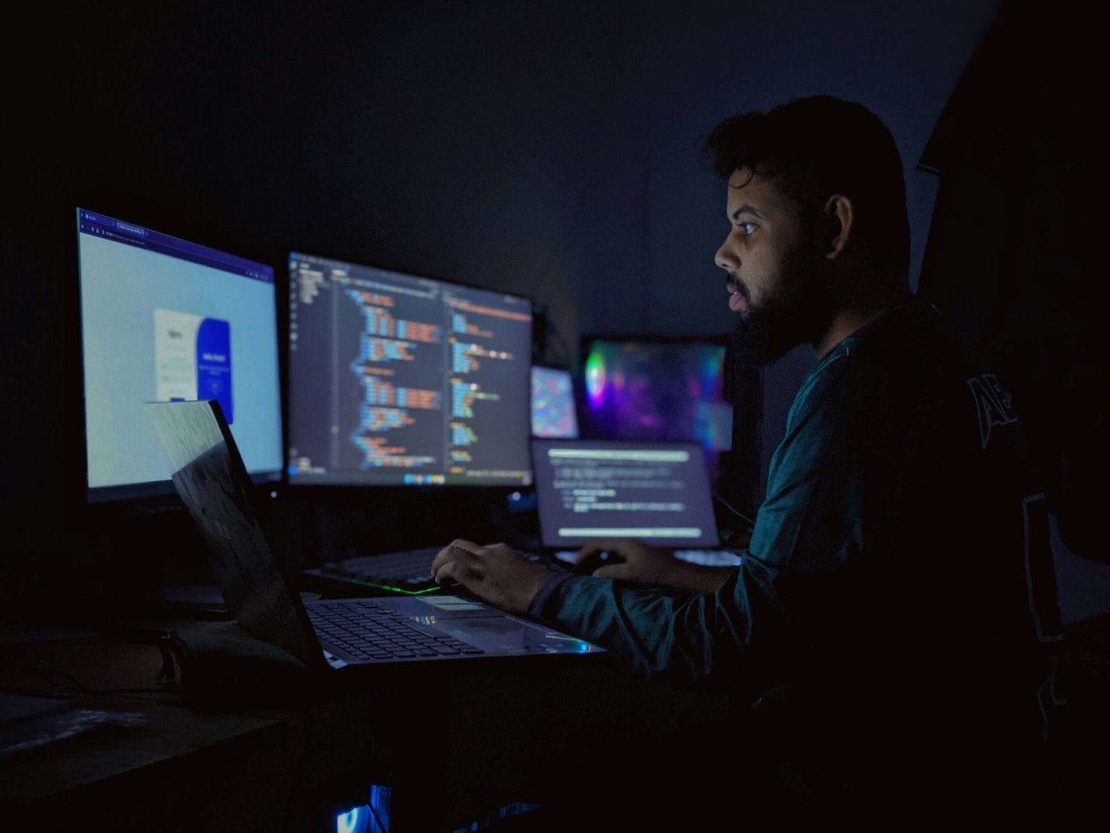 A man sitting in front of three computer monitors