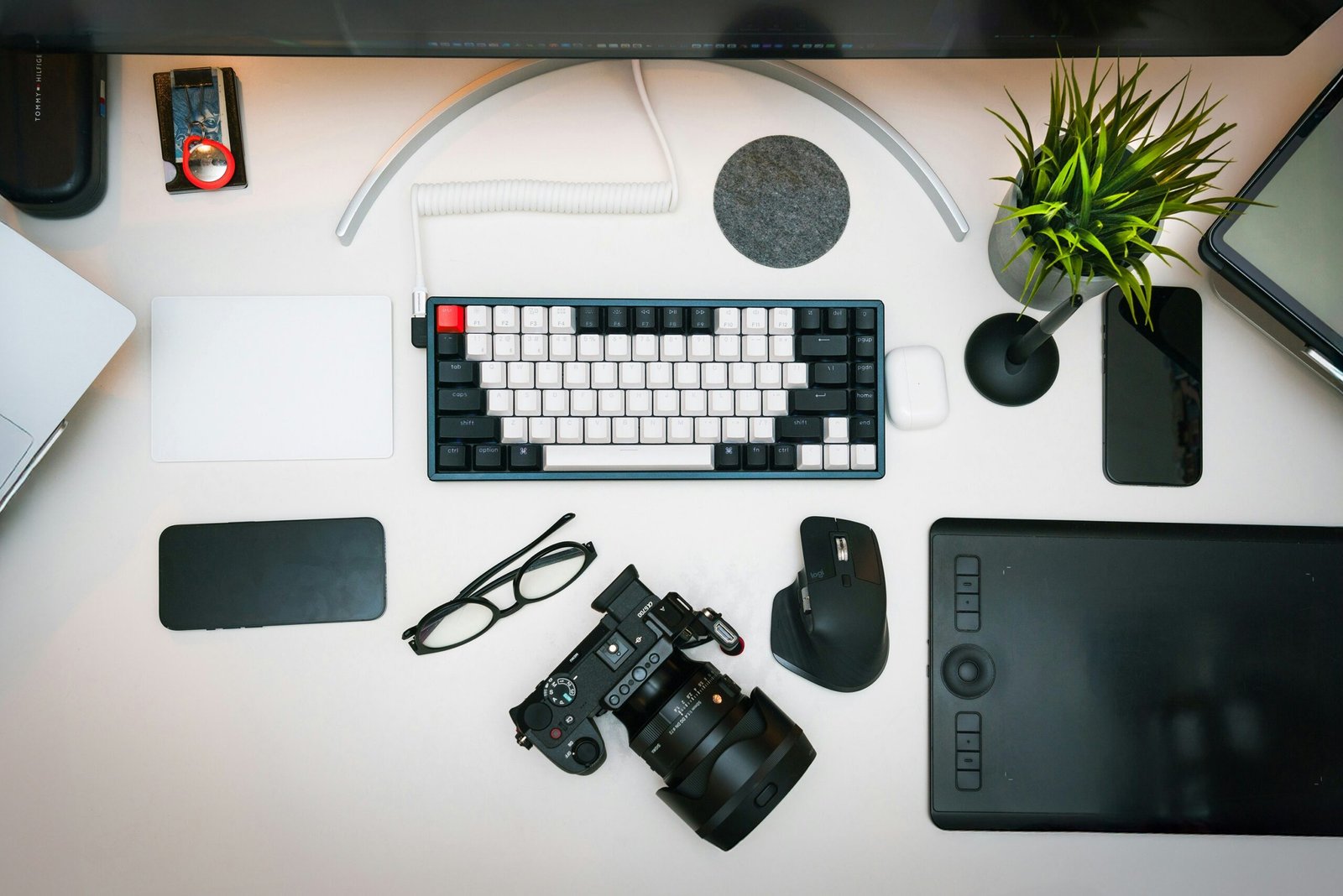 A desk with a keyboard, camera, mouse and other items