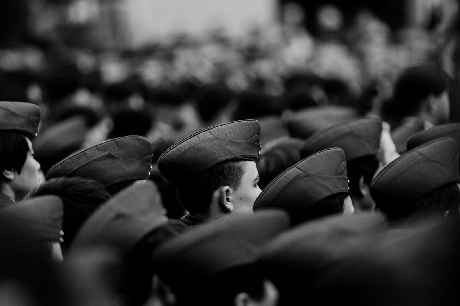 Group of people wearing military caps in black and white.