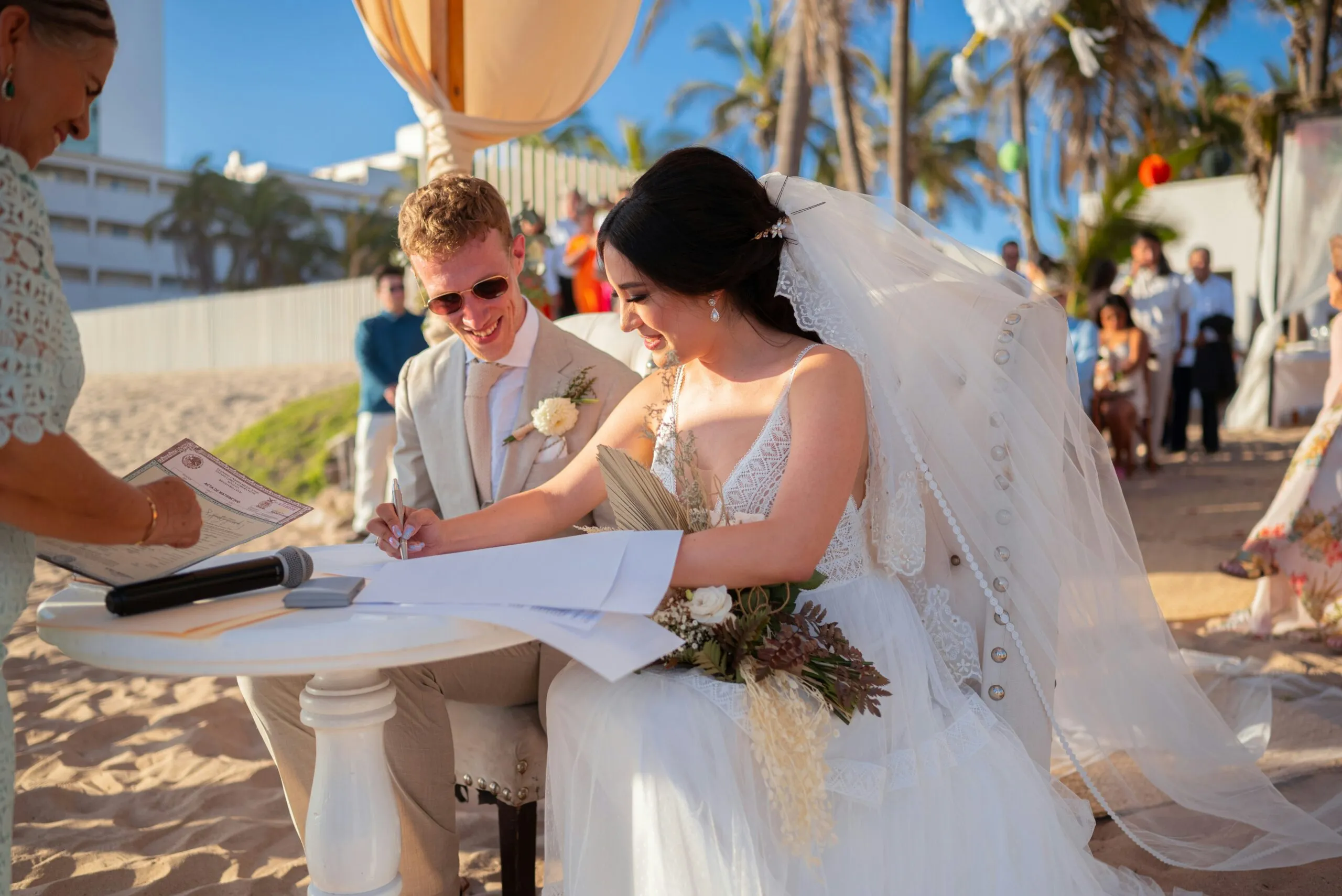 Bride and groom signing wedding certificate on beach.