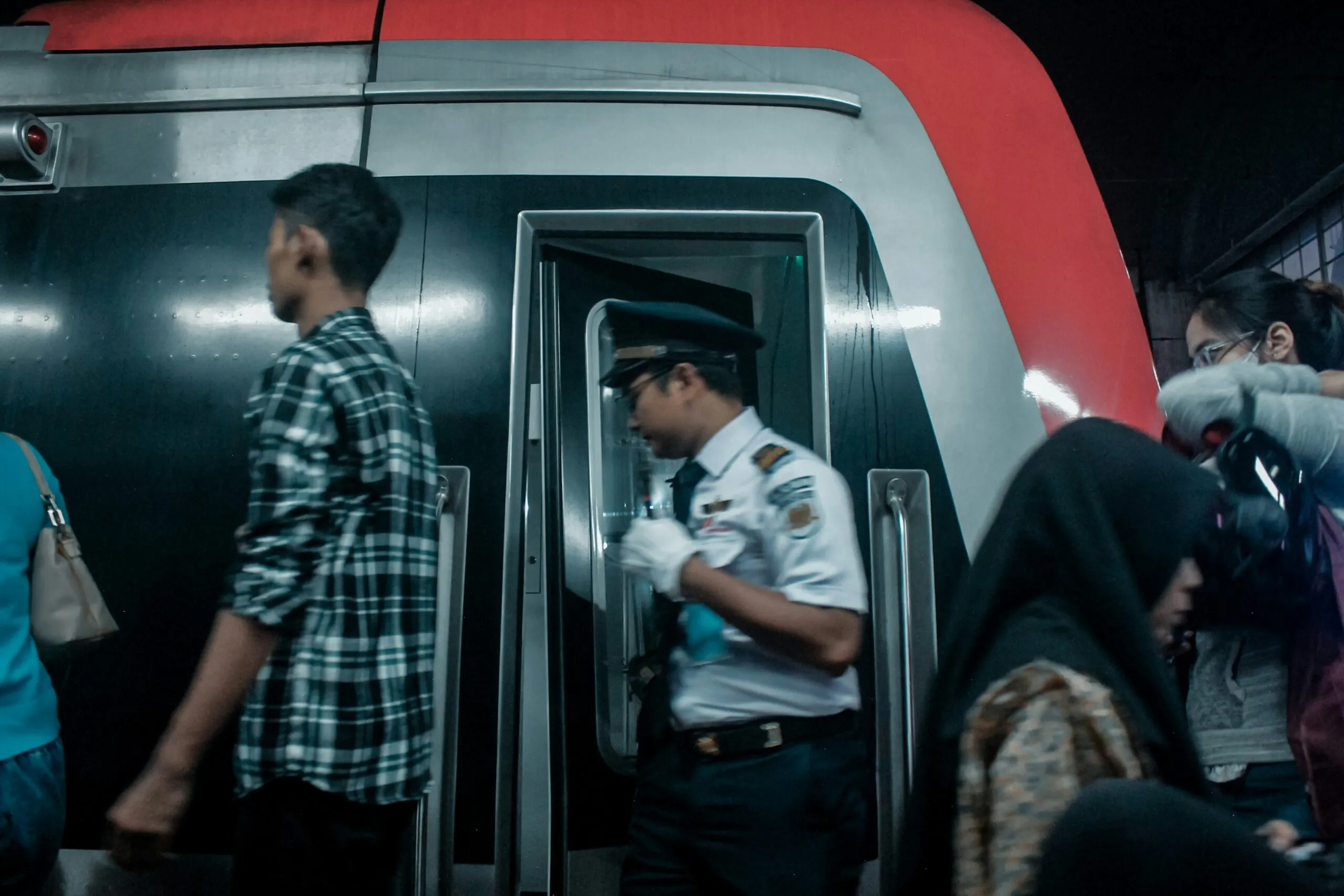 Train conductor and passengers at a station entrance.