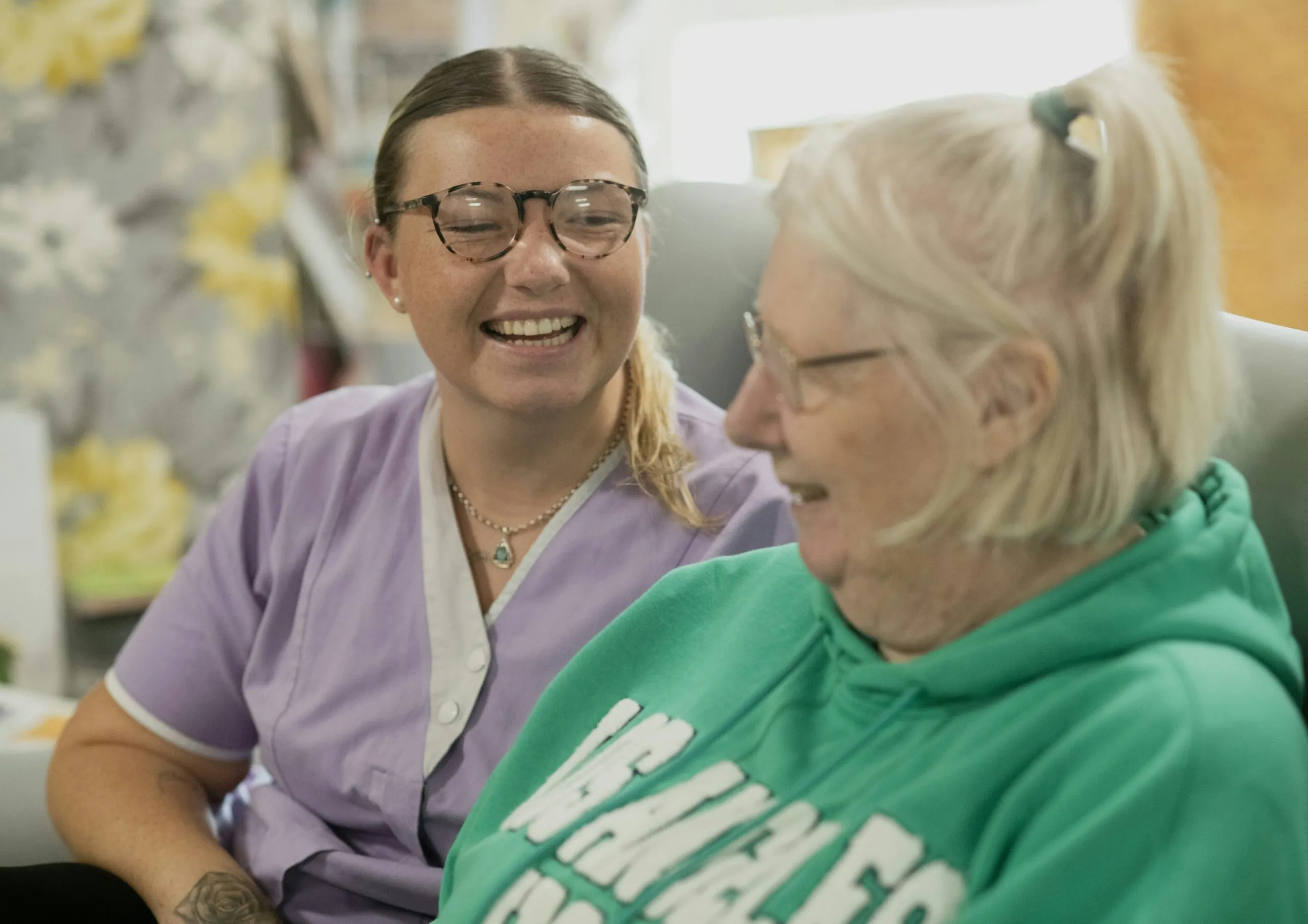 Two women laughing together indoors.