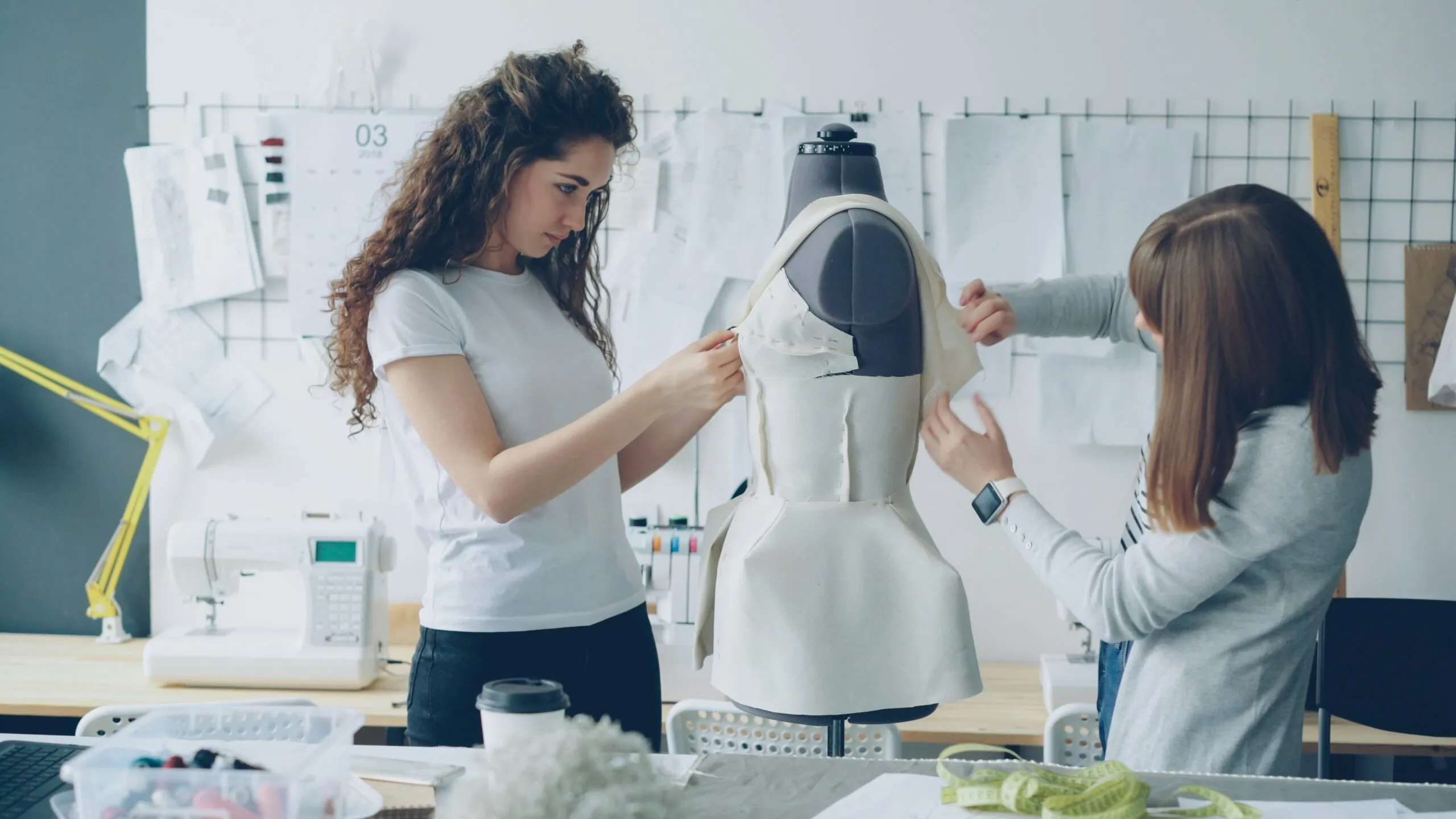 Fashion designers work on a dress form together.