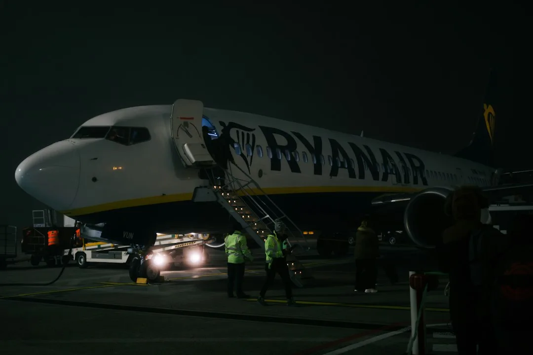 A ryanair plane is boarding passengers at night.