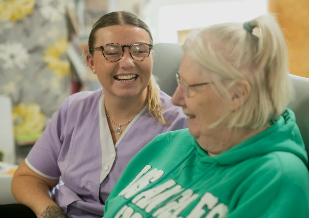 Two women laughing together indoors.