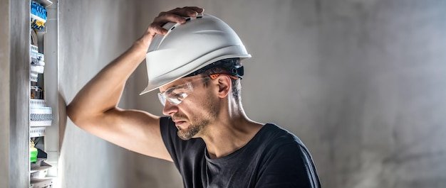 Male electrician working in switchboard with electrical connection cable