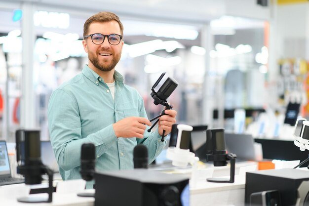 A man chooses a professional microphone to record a video blog Electronics store