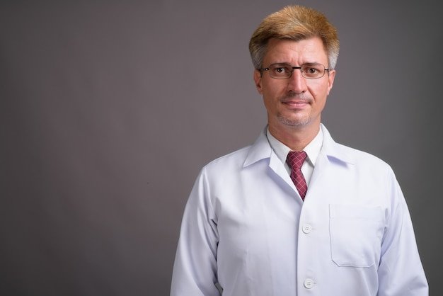 Man doctor with blond hair against gray wall