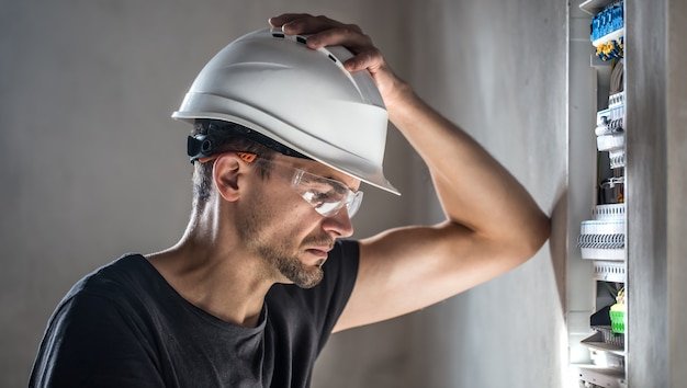 Man, an electrical technician working in a switchboard with fuses. Installation and connection of electrical equipment.