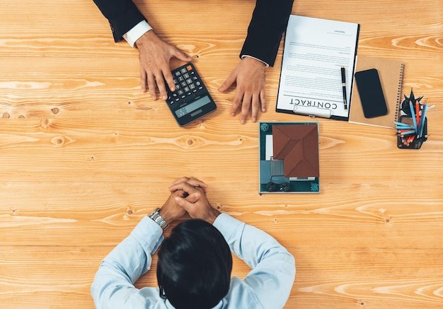 A man sits at a table with a calculator and a pen next to him.