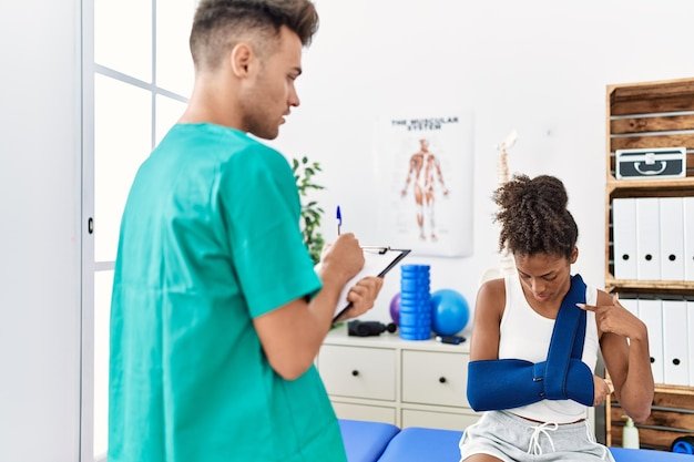 Man and woman wearing physiotherapist uniform having rehab session at physiotherapy clinic