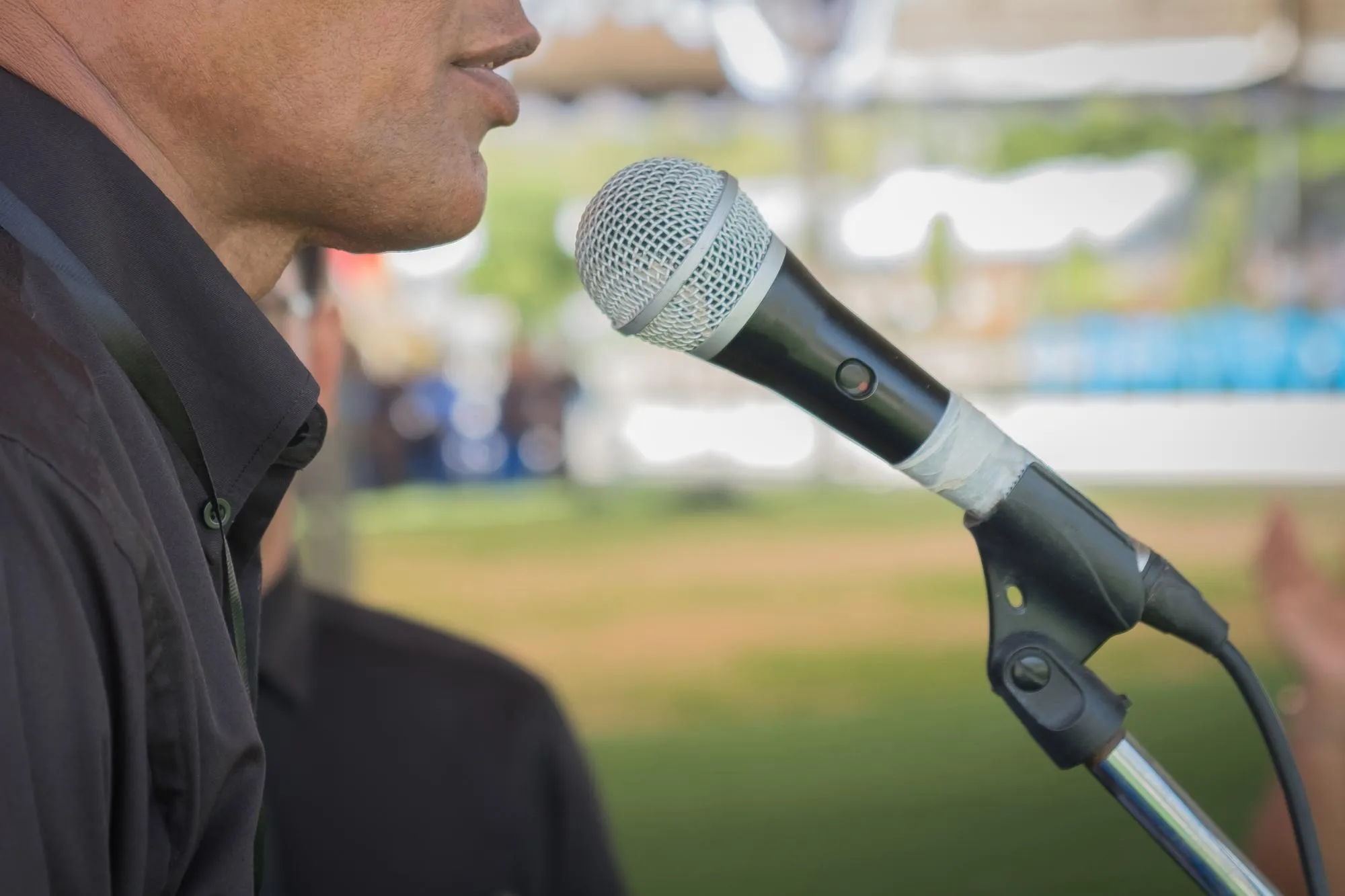 Midsection of man using microphone while standing outdoors