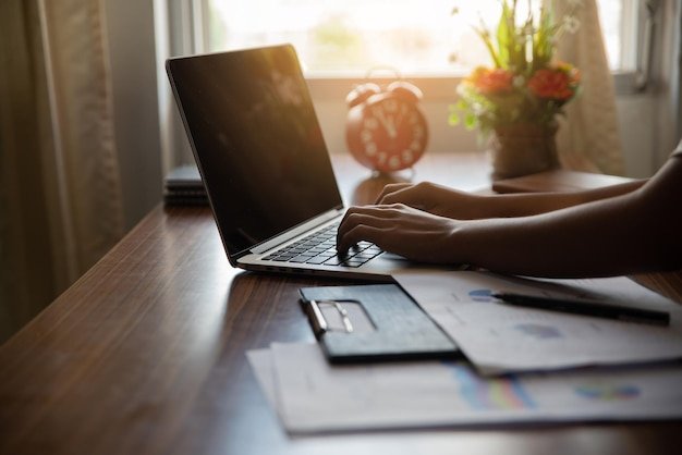 Midsection of person using laptop on table at home