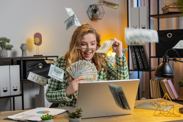 Money cash dollar rain falling on businesswoman with laptop celebrating success win lottery jackpot