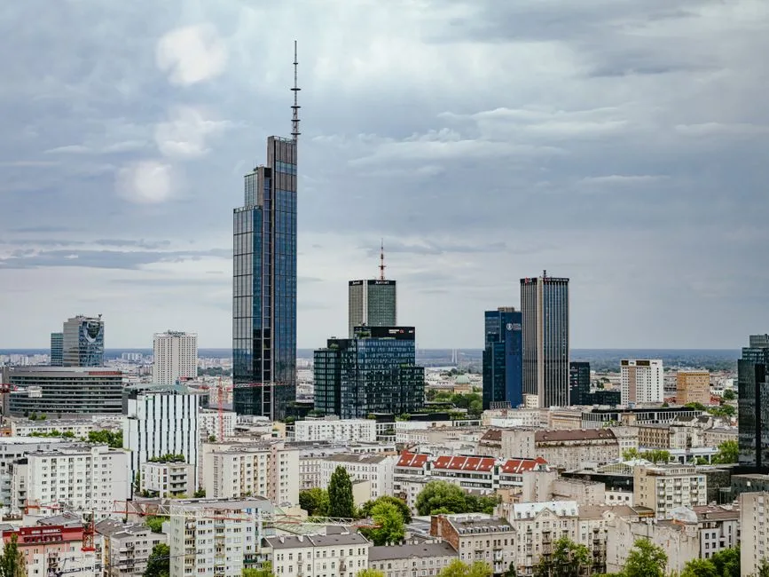 Aerial view of Warsaw's modern skyscrapers under cloudy skies, showcasing urban architecture.