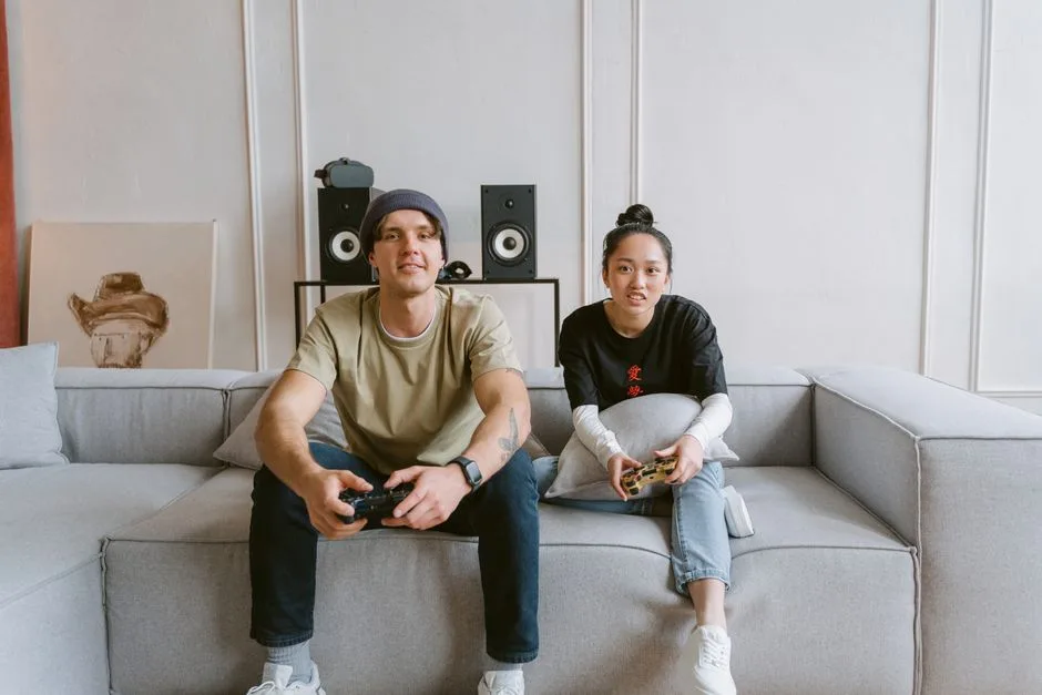 Man and woman playing video games on a couch, conveying a relaxed and fun atmosphere.