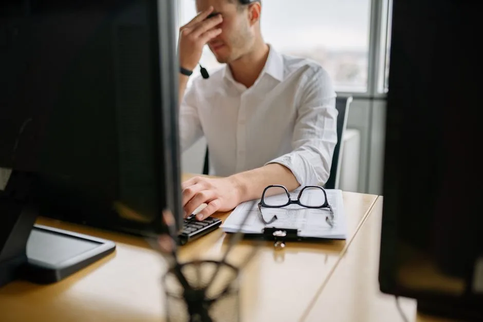 Man at office desk holding head in frustration, signifying stress at work.