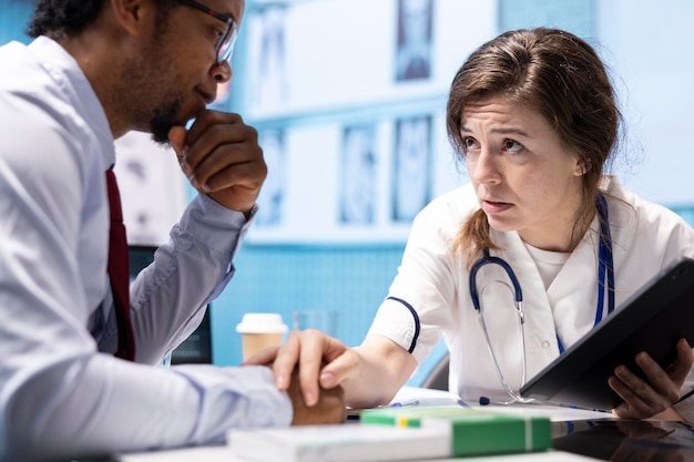Physician comforting her male patient by holding his hand