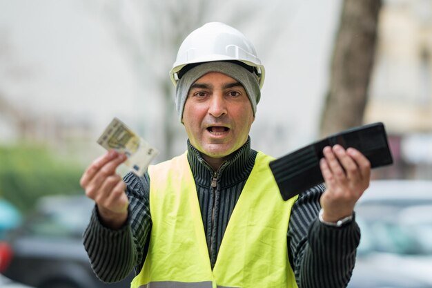 Portrait of engineer in reflective clothing holding currency and wallet