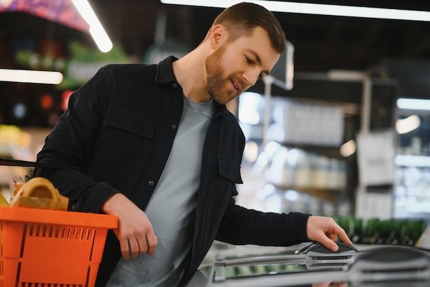 Portrait of smiling man walking with his trolley on aisle at supermarket
