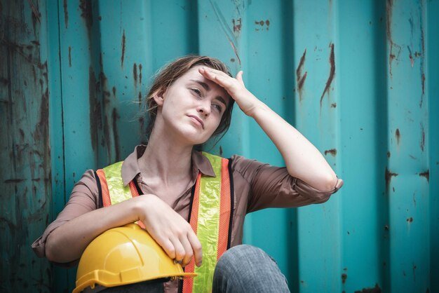 Portrait of smiling young woman sitting against wall