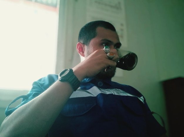 Portrait of young man holding camera at home