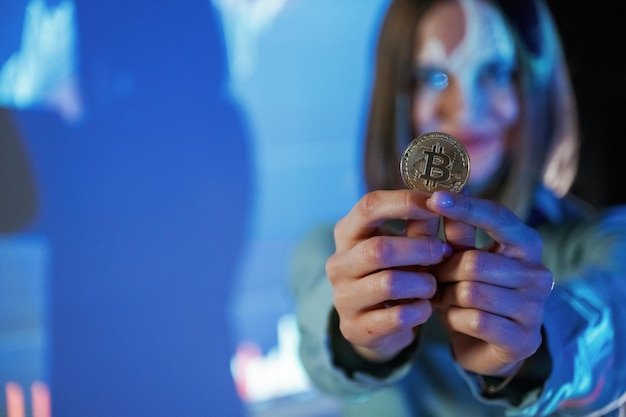 Positive female is with digital currency coin Businesswoman is against projector with graphs indoors