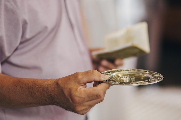 Priest holding plate with stylish wedding rings in church for holy matrimony