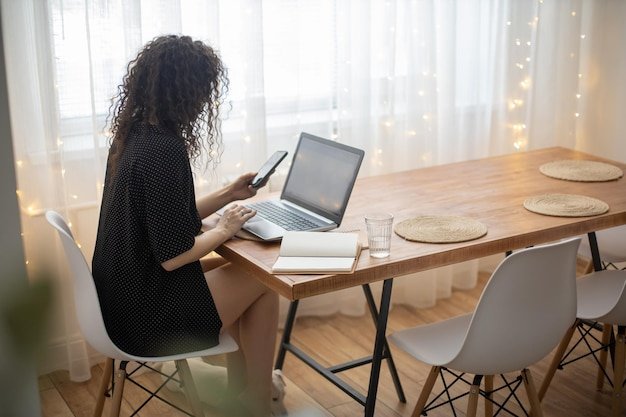 Rear view of woman using laptop on table