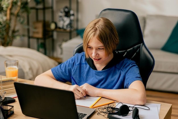 School age boy with spends time in room at desk on chair doing homework in front of computer