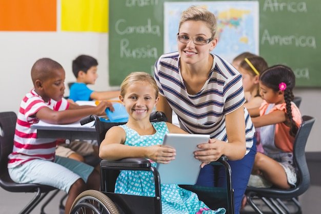 Schoolgirl and teacher using digital tablet in classroom