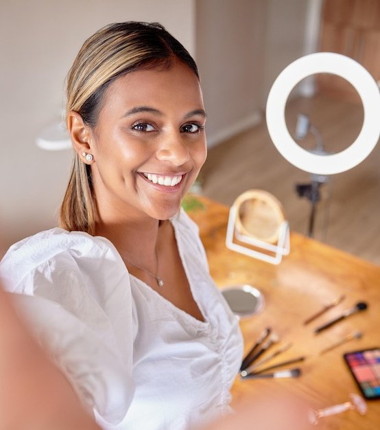 Selfie beauty influencer and makeup tutorial with ring light and gen z person at home Cosmetics video streaming and smile of a young Indian female with cosmetic mobile and online social media