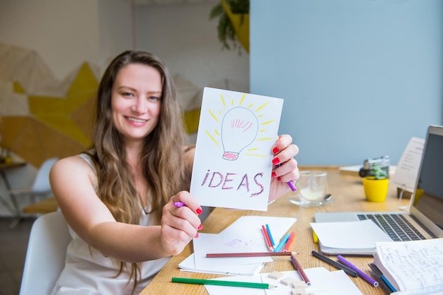 Smiling young woman using smart phone on table