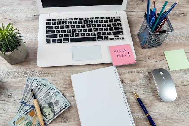 Stiket with text need help dolar and laptop on office desk