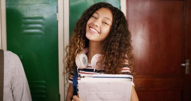 Student girl and portrait with book in high school for learning education and ready for class Scholarship teenager and smile in hallway for knowledge academic development and study opportunity
