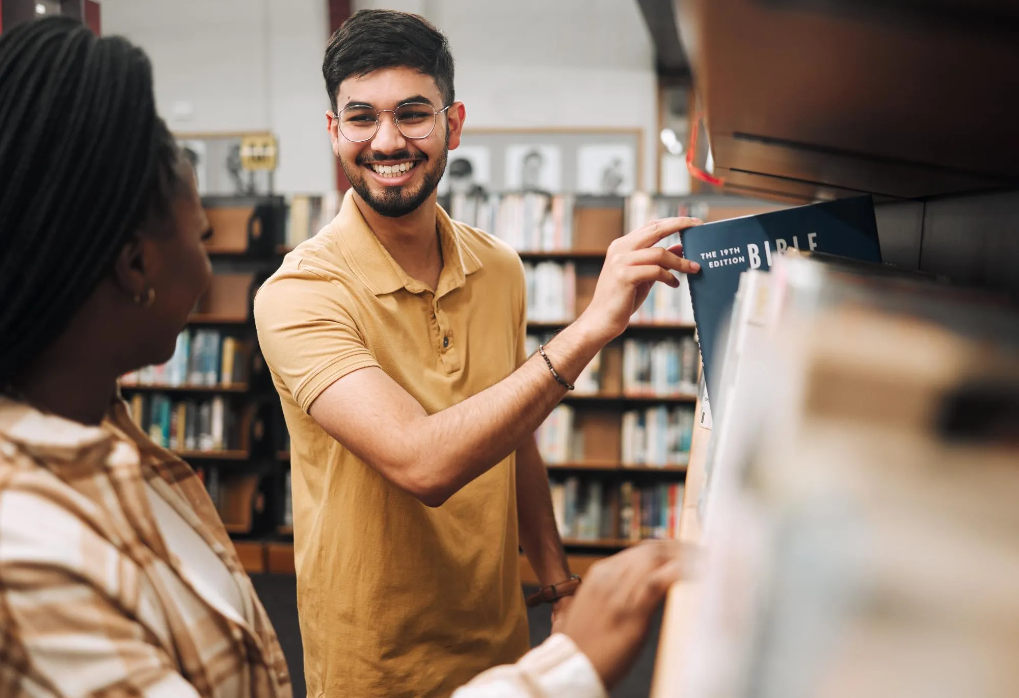 Studying religion research and students in library college bookshelf and happy with knowledge on campus Smile choice and couple of friends with scholarship for learning education and university