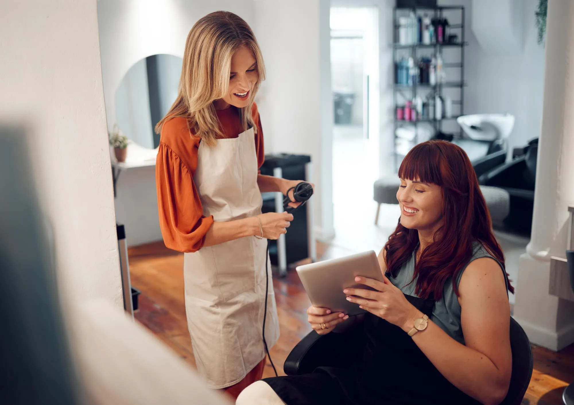 Tablet salon hairdresser and customer show hairstylist hair cut idea on digital device Happy woman client smile and ready for consultation and professional haircare treatment in luxury boutique