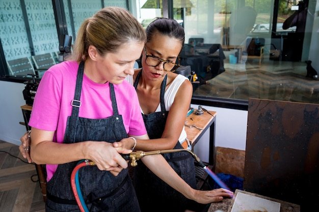 Teacher jeweler and student using burner in workshop