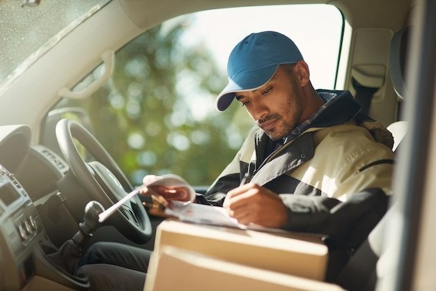 Updating his delivery status Shot of a delivery man reading addresses while sitting in a delivery van