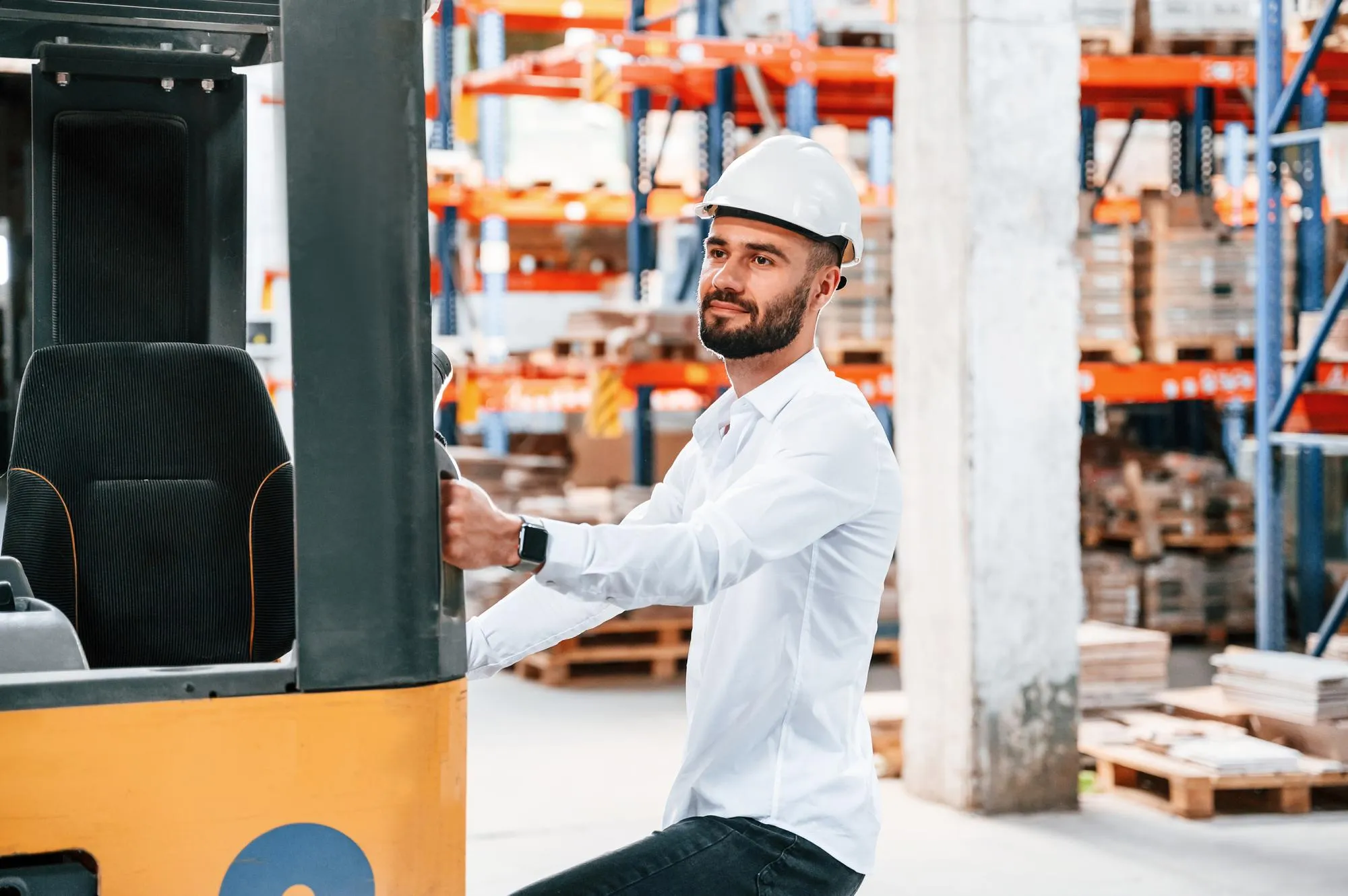 Using cargo moving machine Storage worker is in the warehouse with bunch of products