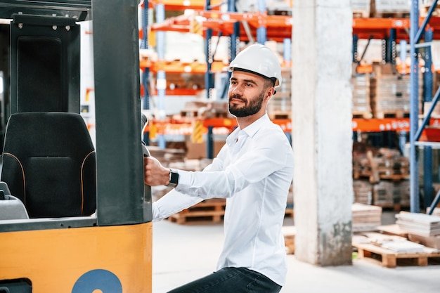 Using cargo moving machine Storage worker is in the warehouse with bunch of products