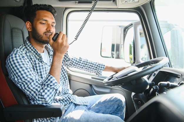 Using radio Young truck driver is with his vehicle at daytime