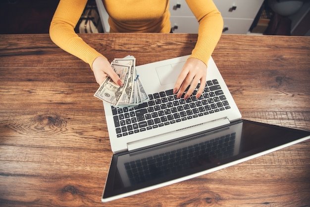 Woman hand money and computer on table