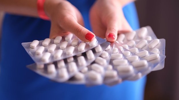 Woman is holding lot of pills in blister