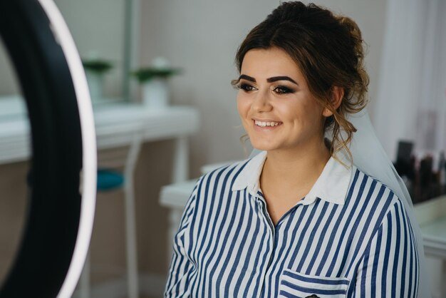 A woman looks at her makeup mirror in a photo studio.