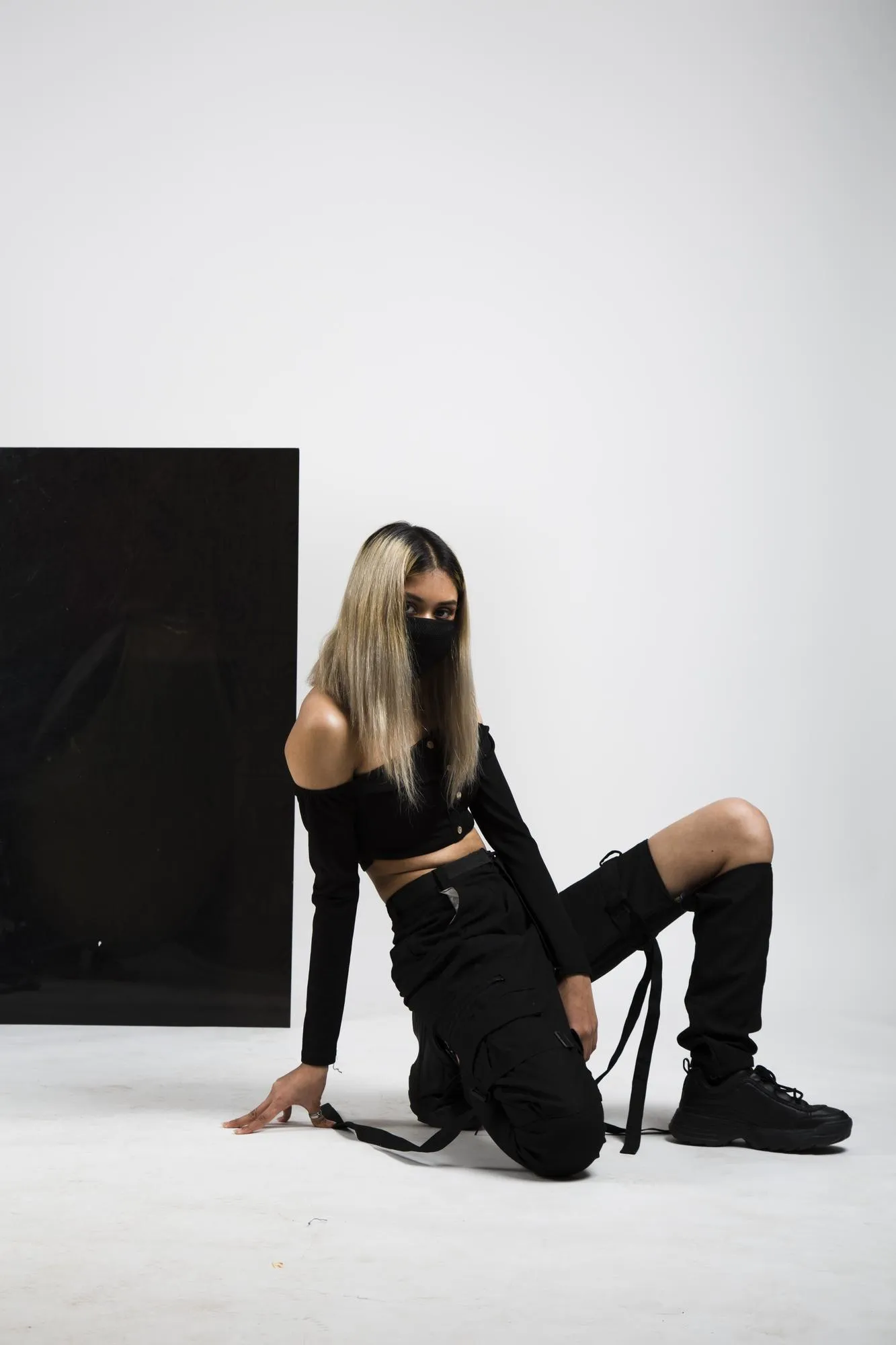 Woman model Posing in Black outfit wearing mask with black background