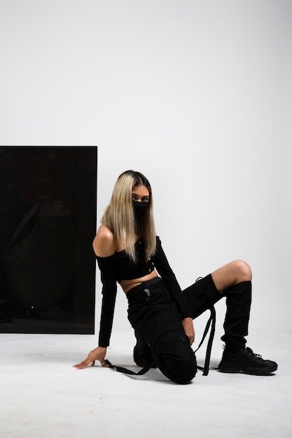 Woman model Posing in Black outfit wearing mask with black background