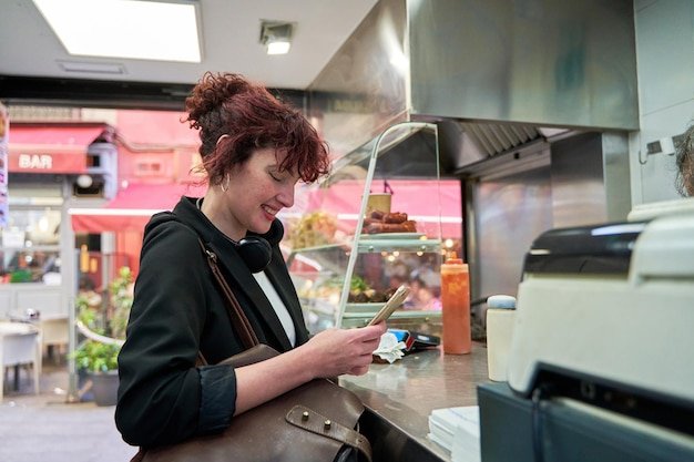 woman sitting at a bar counter holding her mobile phone in hand as she browses the menu